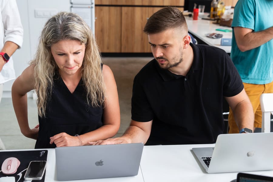 Two colleagues working through a problem together on a laptop