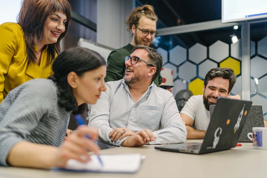 Team members laughing together around a desk
